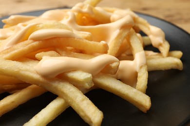 Photo of Delicious French fries with cheese sauce on plate, closeup