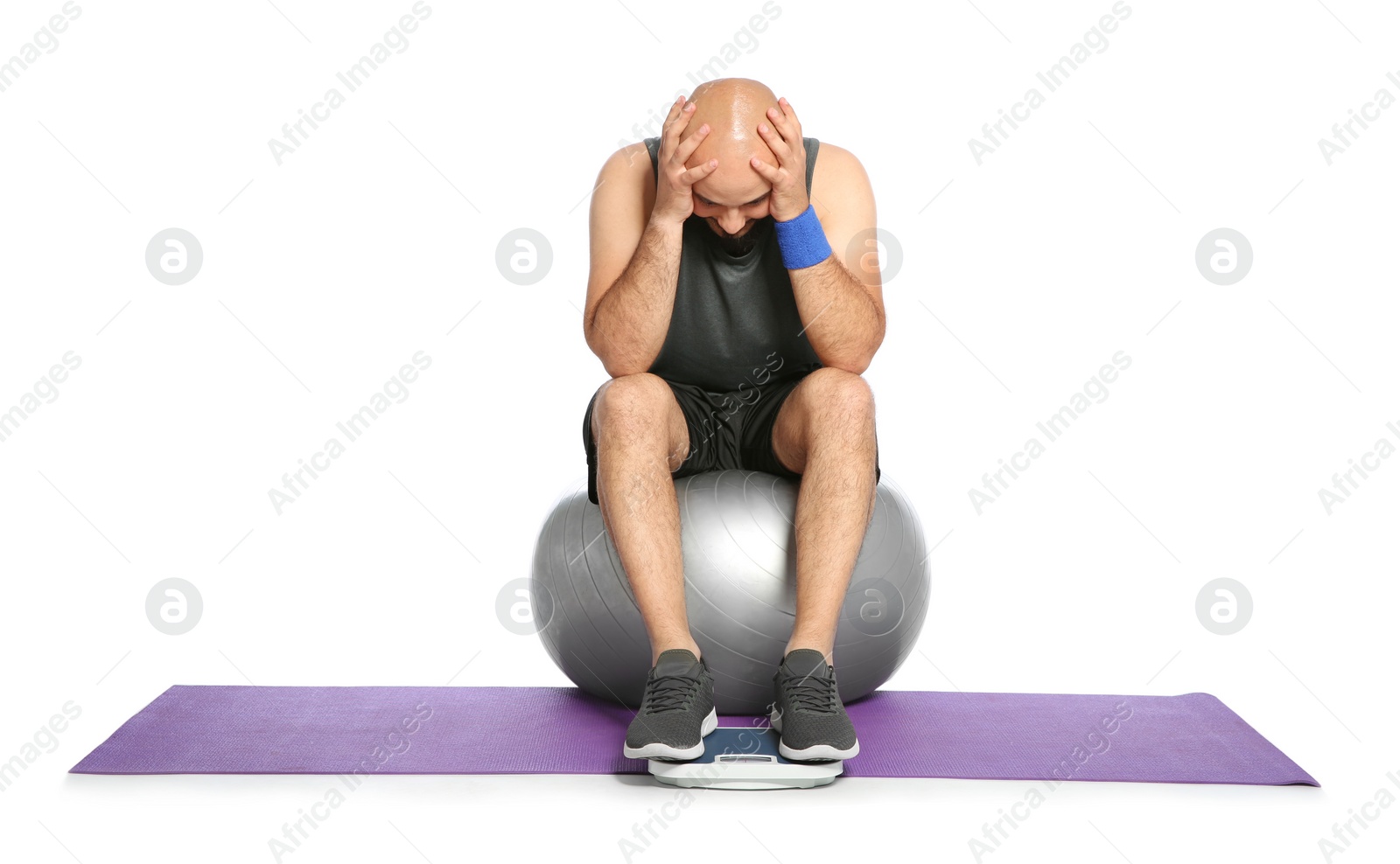 Photo of Upset overweight man with scale and fitness ball on white background
