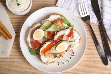 Delicious bruschettas with salmon served on wooden table, flat lay