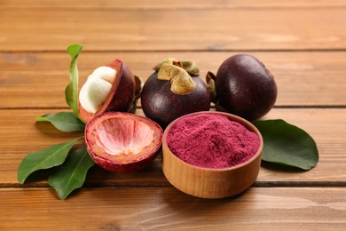 Photo of Purple mangosteen powder and fruits on wooden table