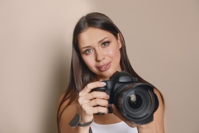 Professional photographer with camera on beige background