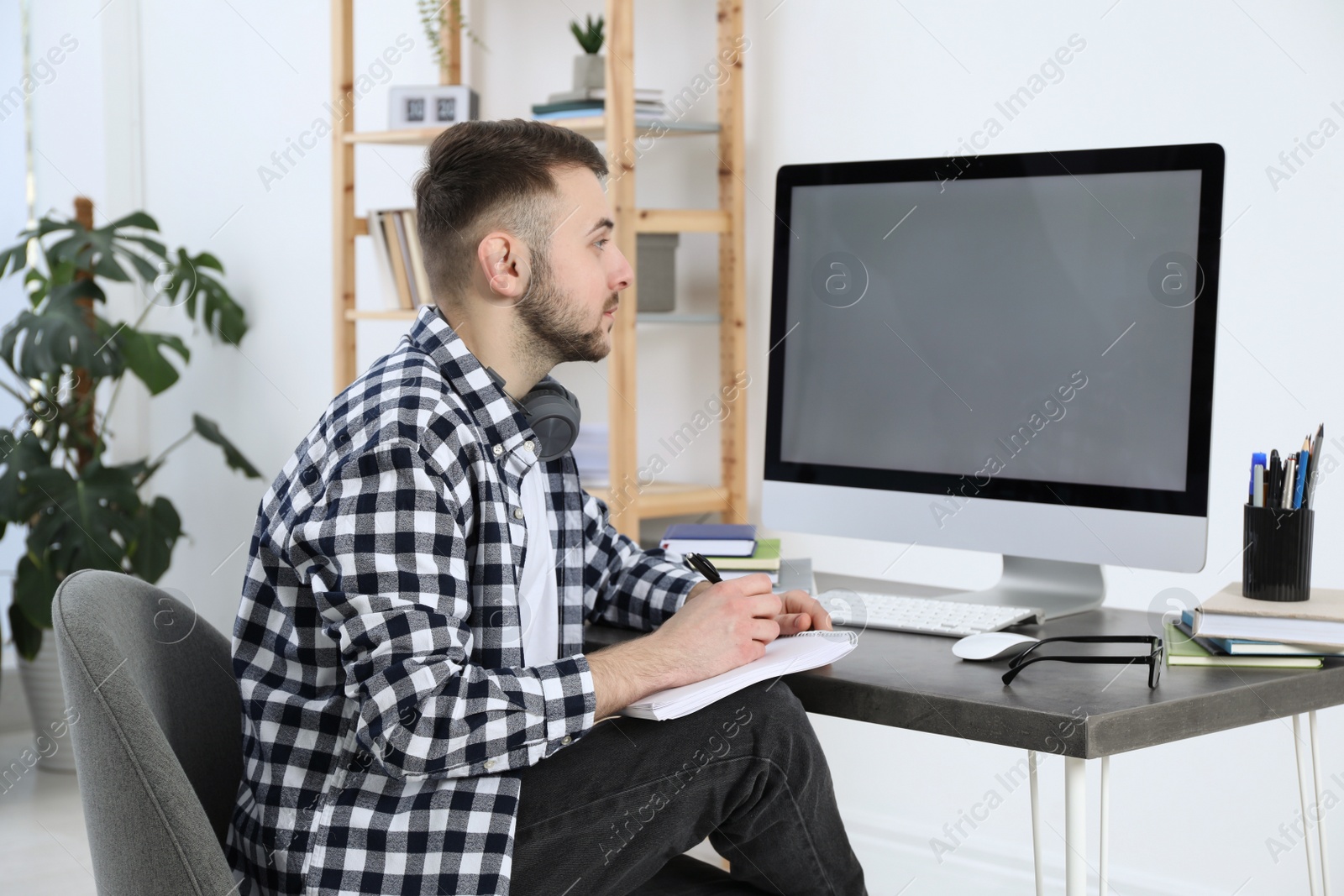 Photo of Young man using modern computer for studying at home. Distance learning