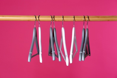 Photo of Wooden rack with clothes hangers on color background
