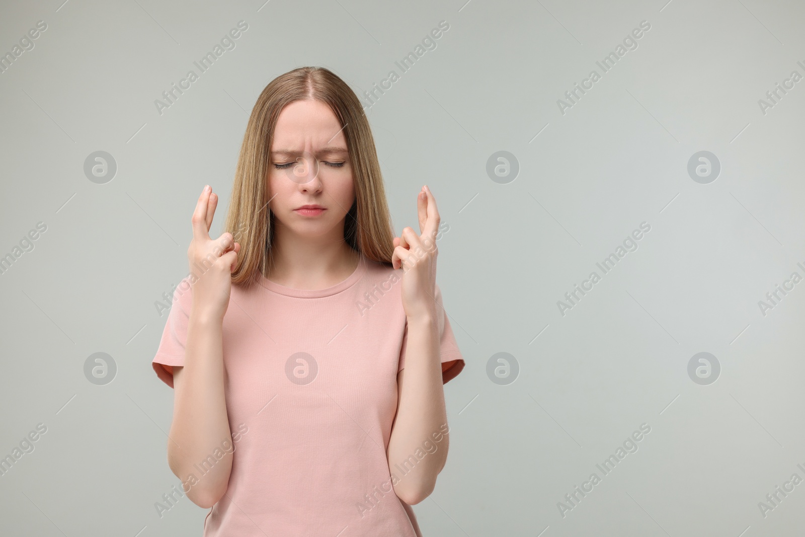 Photo of Woman crossing her fingers on grey background, space for text