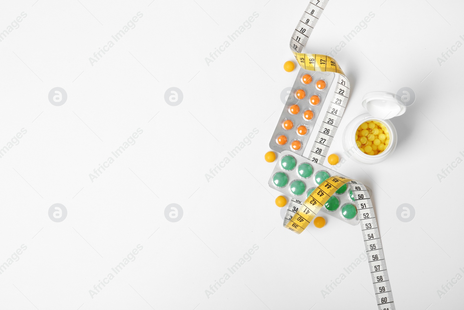 Photo of Composition with Weight loss pills and measuring tape on white background, top view. Space for text