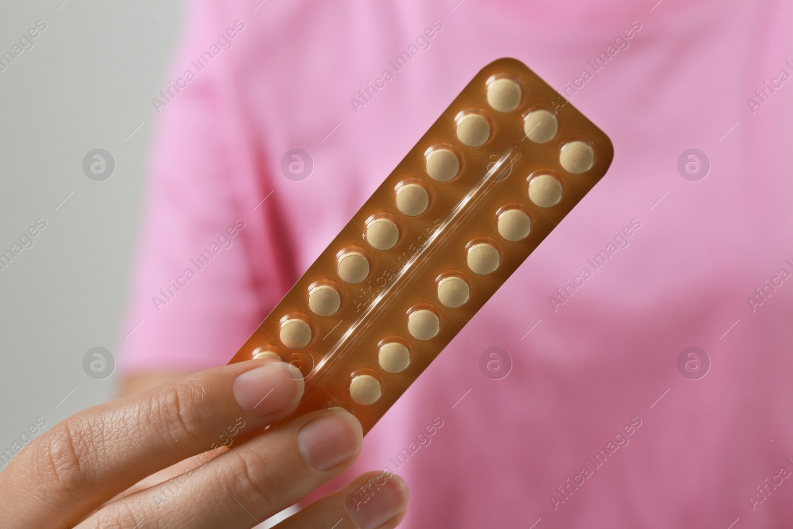 Photo of Woman holding birth control pills on grey background, closeup