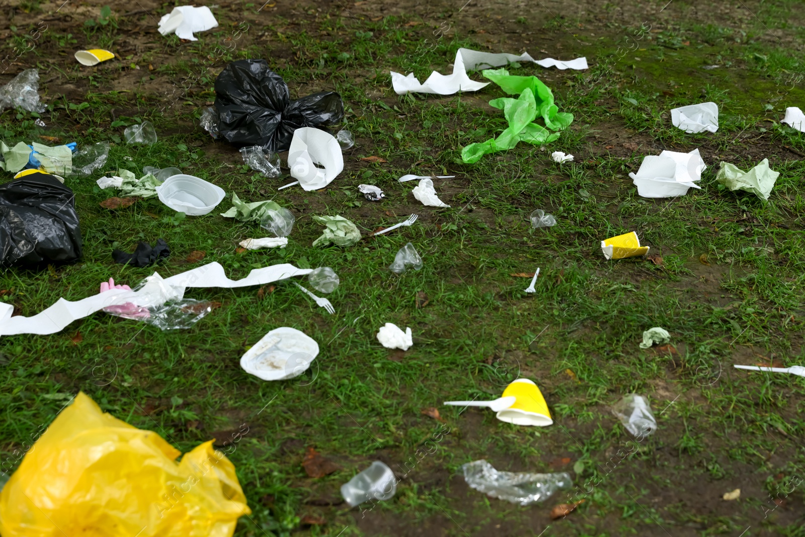 Photo of Different garbage scattered on green grass outdoors