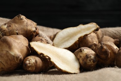 Jerusalem artichokes on bag against dark background, closeup