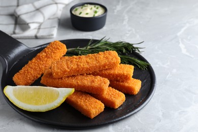 Photo of Fresh breaded fish fingers and lemon served on light grey table