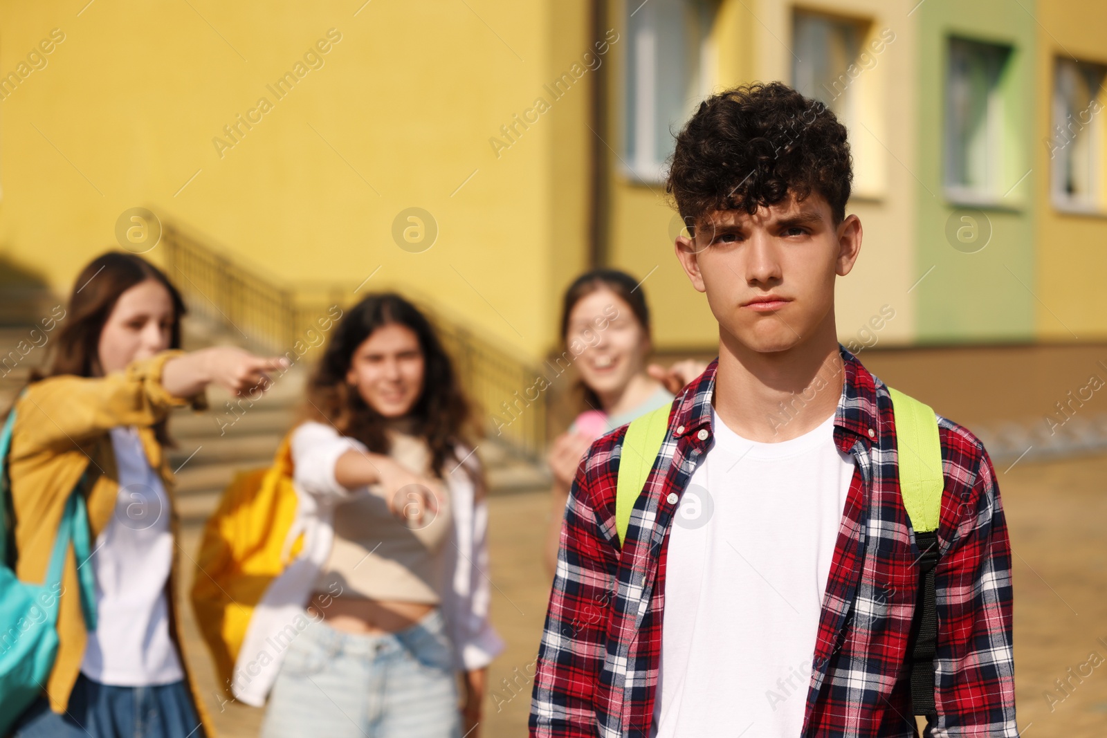Photo of Teen problems. Group of students pointing at upset boy outdoors, selective focus