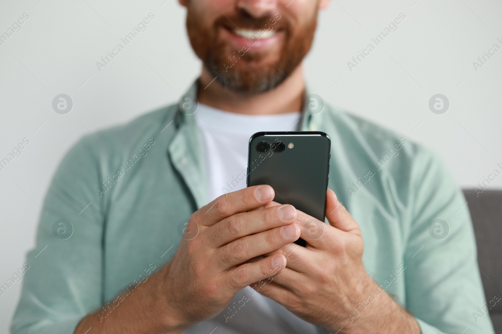 Photo of Man using smartphone at home, closeup view