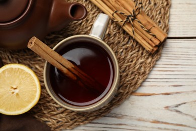 Photo of Delicious hot tea with cinnamon and lemon on white wooden table, flat lay