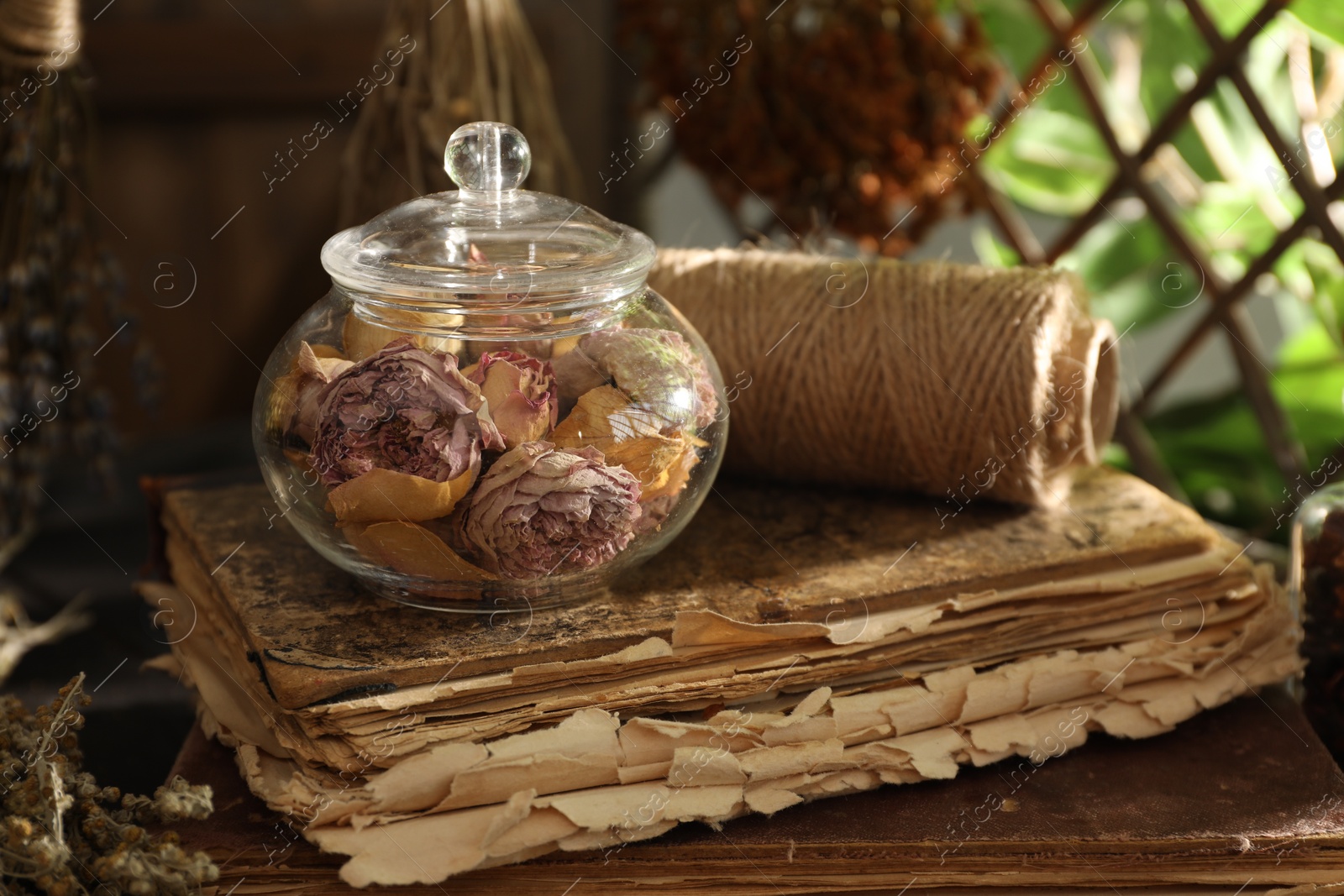 Photo of Dry roses, old book and spool of thread on wooden table indoors