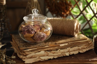 Photo of Dry roses, old book and spool of thread on wooden table indoors