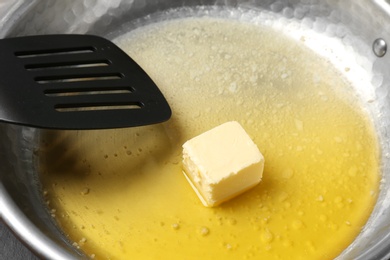 Photo of Frying pan with melting butter and spatula, closeup
