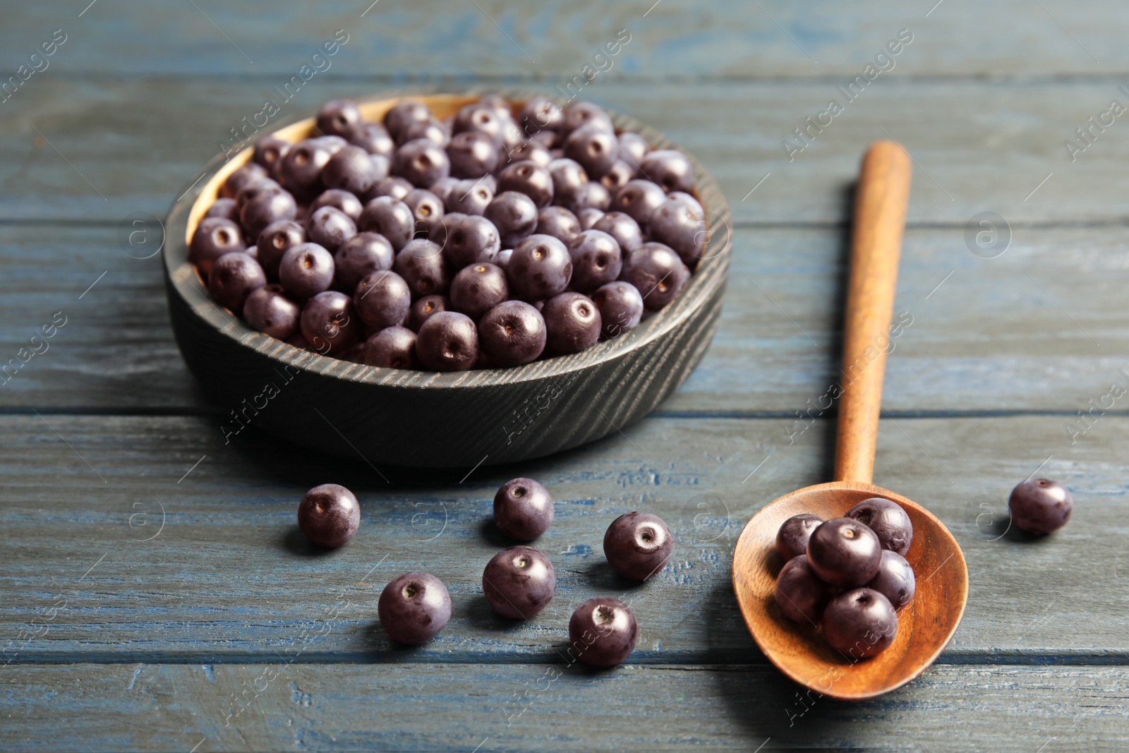 Photo of Plate and spoon with fresh acai berries on wooden table