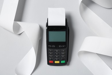 Photo of Payment terminal with thermal paper for receipt on light grey background, top view