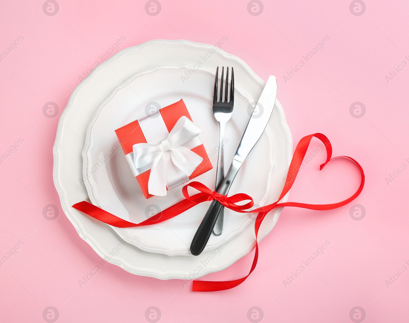 Photo of Beautiful table setting for Valentine's Day dinner on pink background, flat lay