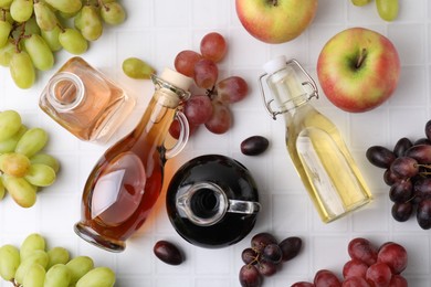 Different types of vinegar and ingredients on light tiled table, flat lay