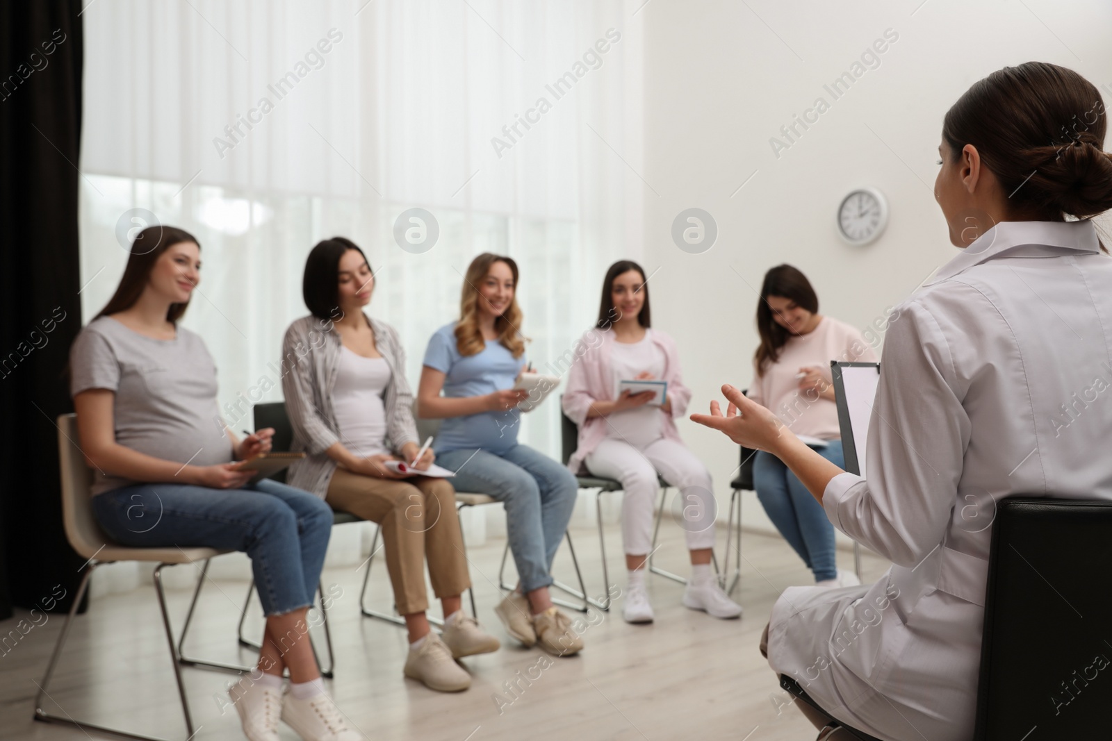 Photo of Group of pregnant women with doctor at courses for expectant mothers indoors