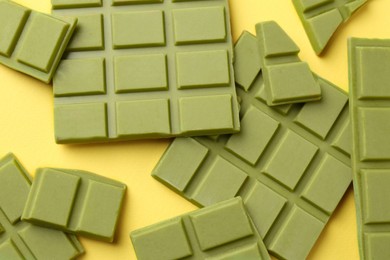 Photo of Pieces of tasty matcha chocolate bars on yellow background, top view