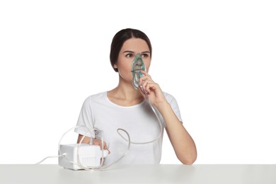 Photo of Young woman using nebulizer at table on white background