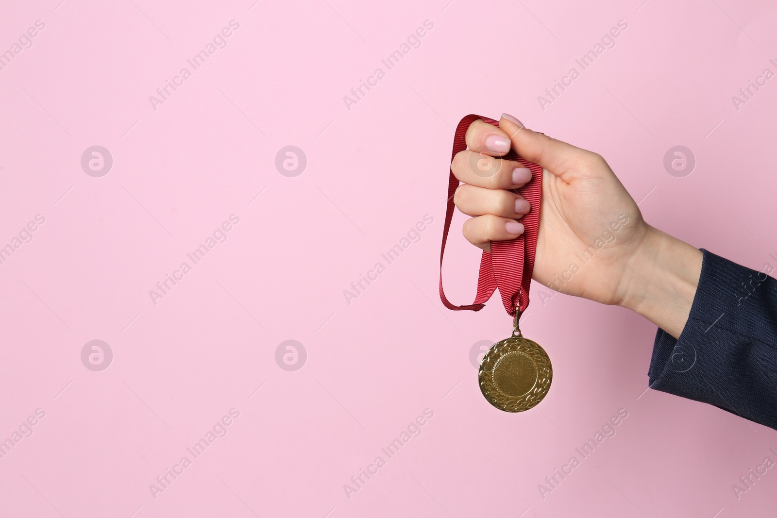 Photo of Woman holding golden medal on color background, closeup. Space for text