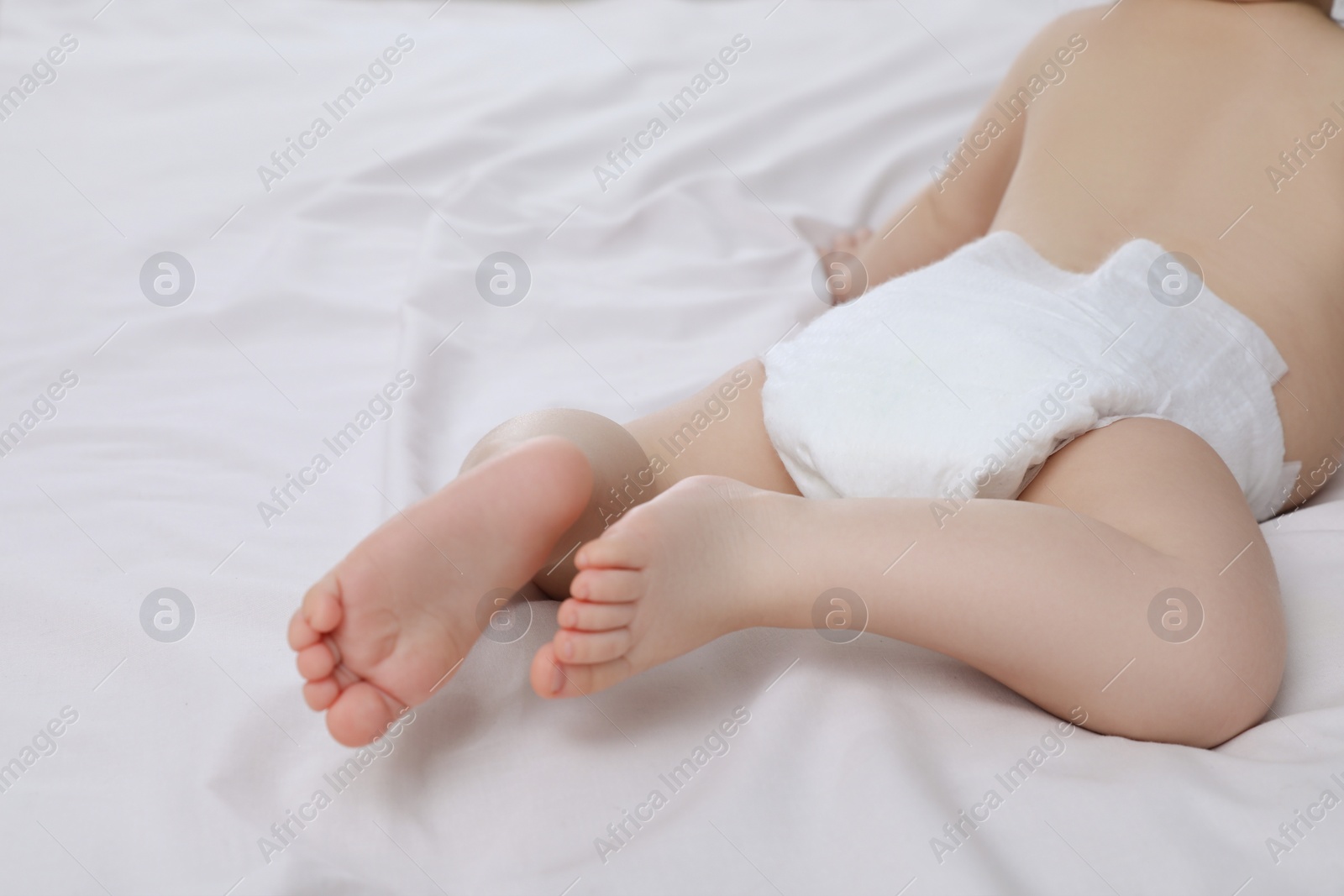 Photo of Little baby in diaper lying on bed, closeup