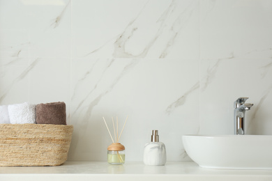 Bathroom counter with sink, soap dispenser, reed air freshener and towels