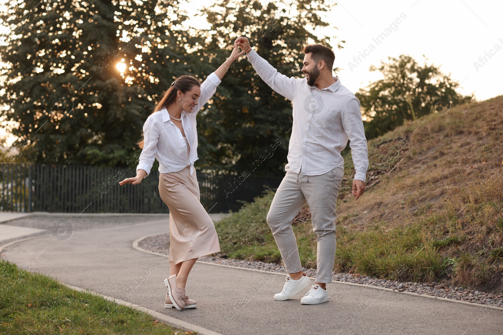 Photo of Lovely couple dancing together outdoors at sunset