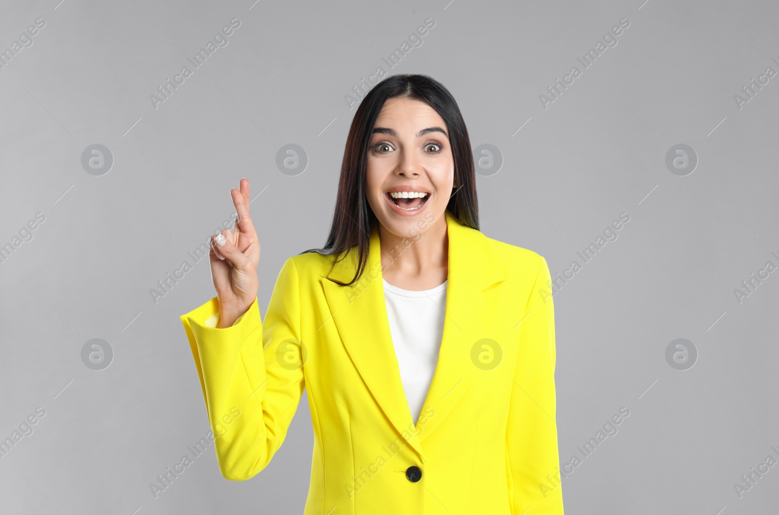 Photo of Woman with crossed fingers on grey background. Superstition concept