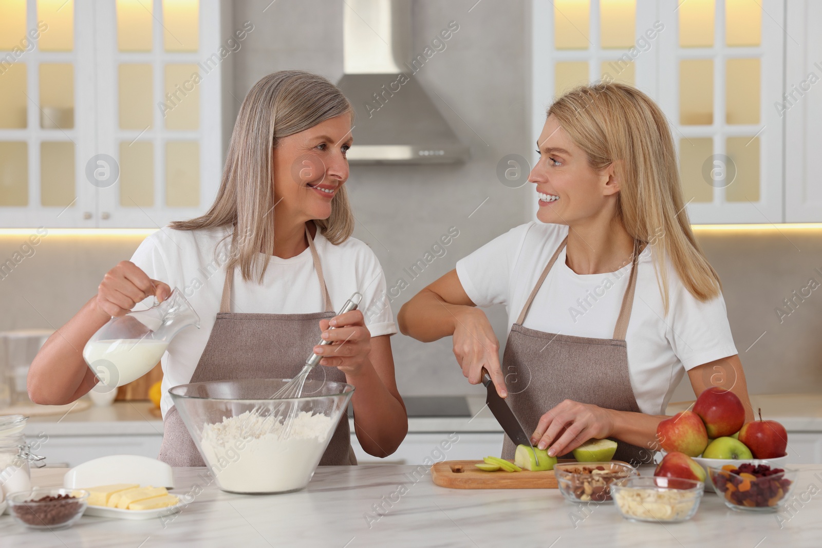 Photo of Happy mature mother and her daughter cooking together at kitchen