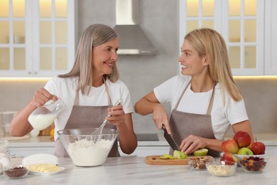 Happy mature mother and her daughter cooking together at kitchen