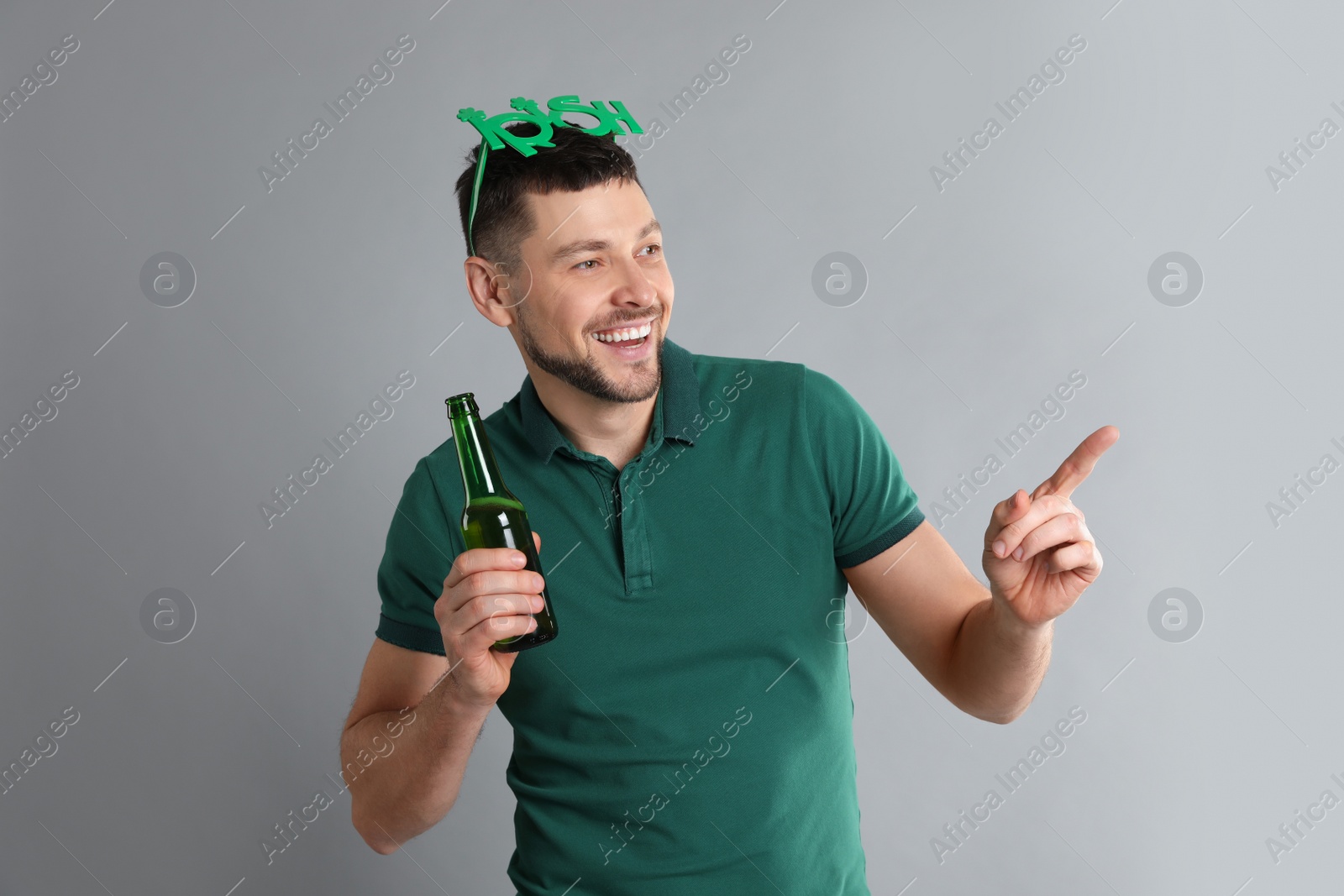 Photo of Happy man in St Patrick's Day outfit with beer on light grey background