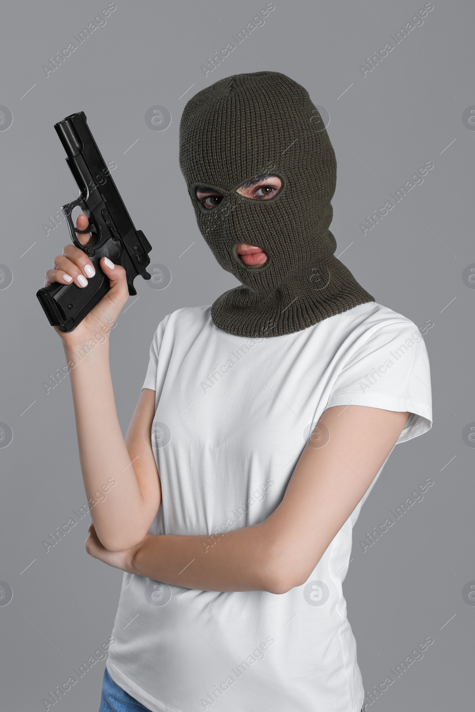 Photo of Woman wearing knitted balaclava with gun on grey background