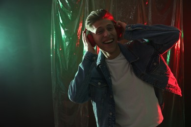 Young man with headphones in neon lights. Space for text