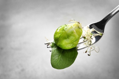 Fork with delicious Brussels sprouts salad on grey background, closeup. Space for text