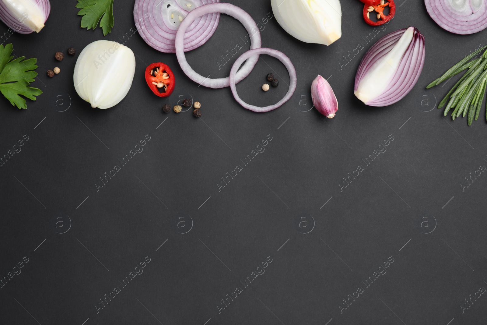 Photo of Flat lay composition with slices of onion and spices on black background. Space for text