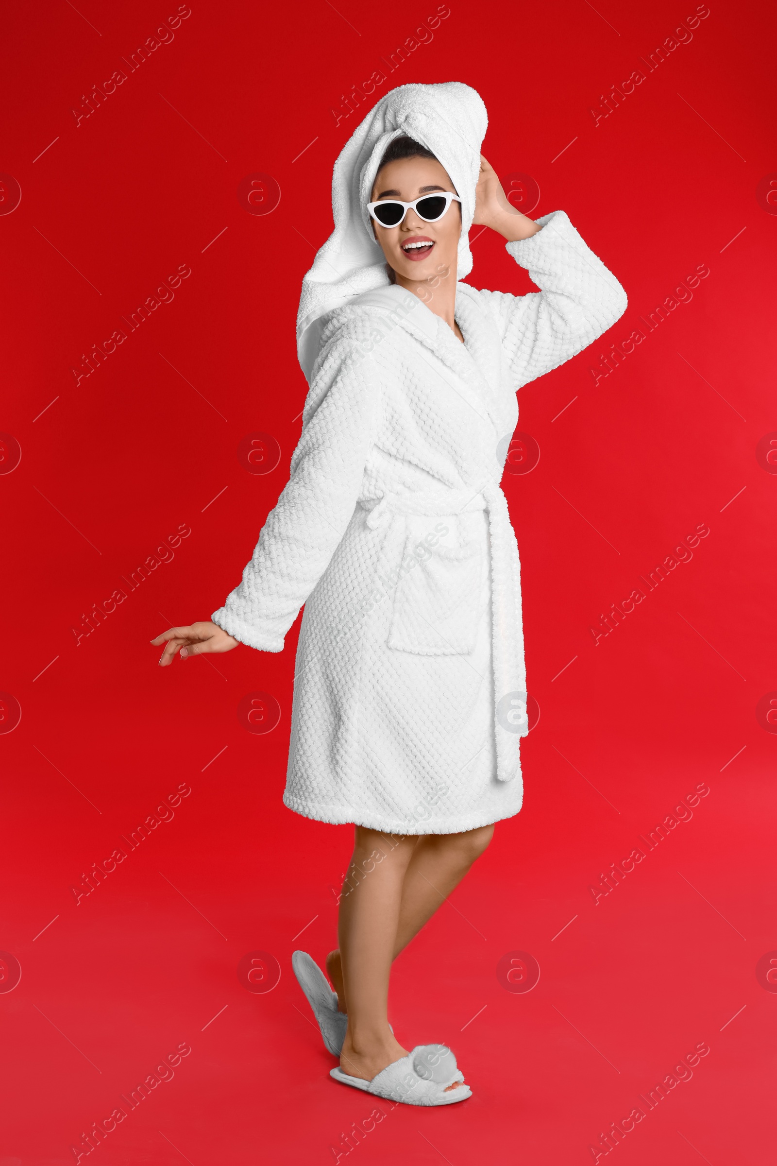 Photo of Beautiful young woman in bathrobe and sunglasses on red background