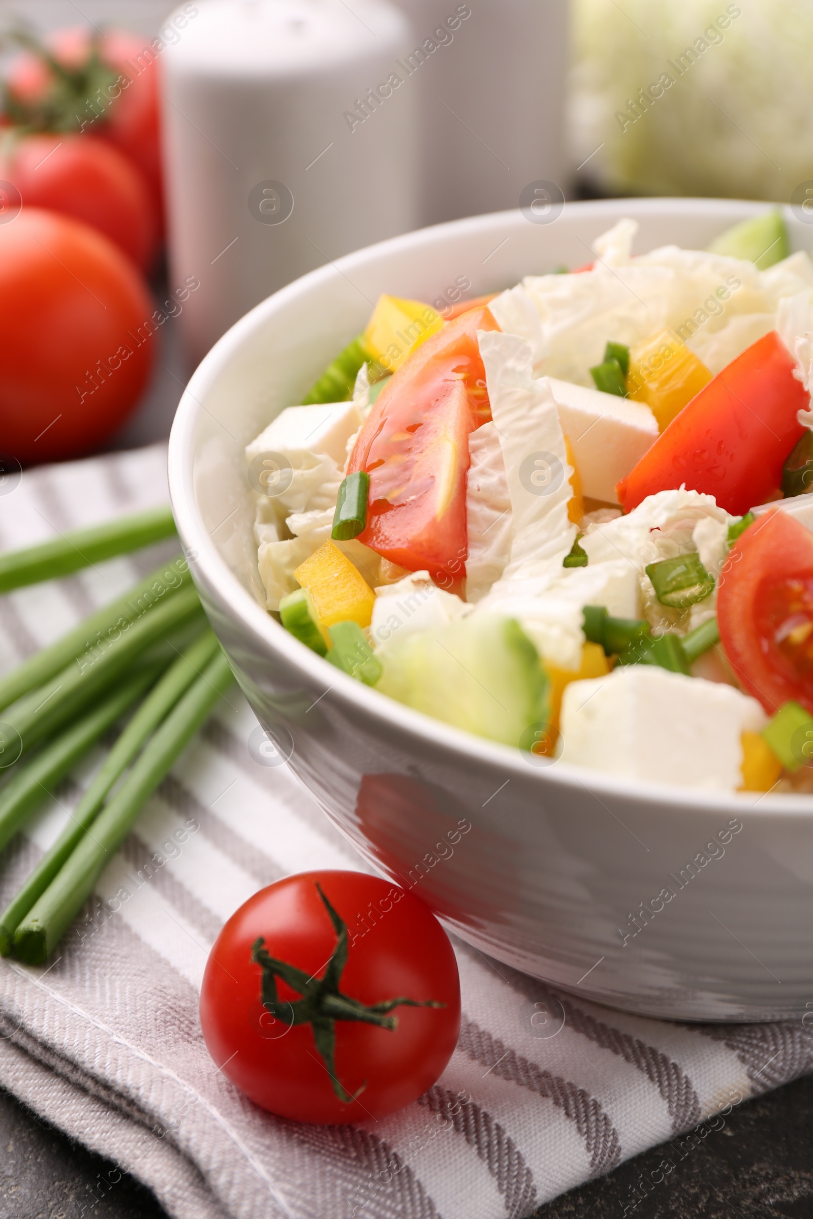 Photo of Tasty salad with Chinese cabbage, cheese, pepper, tomato and green onion on table, closeup