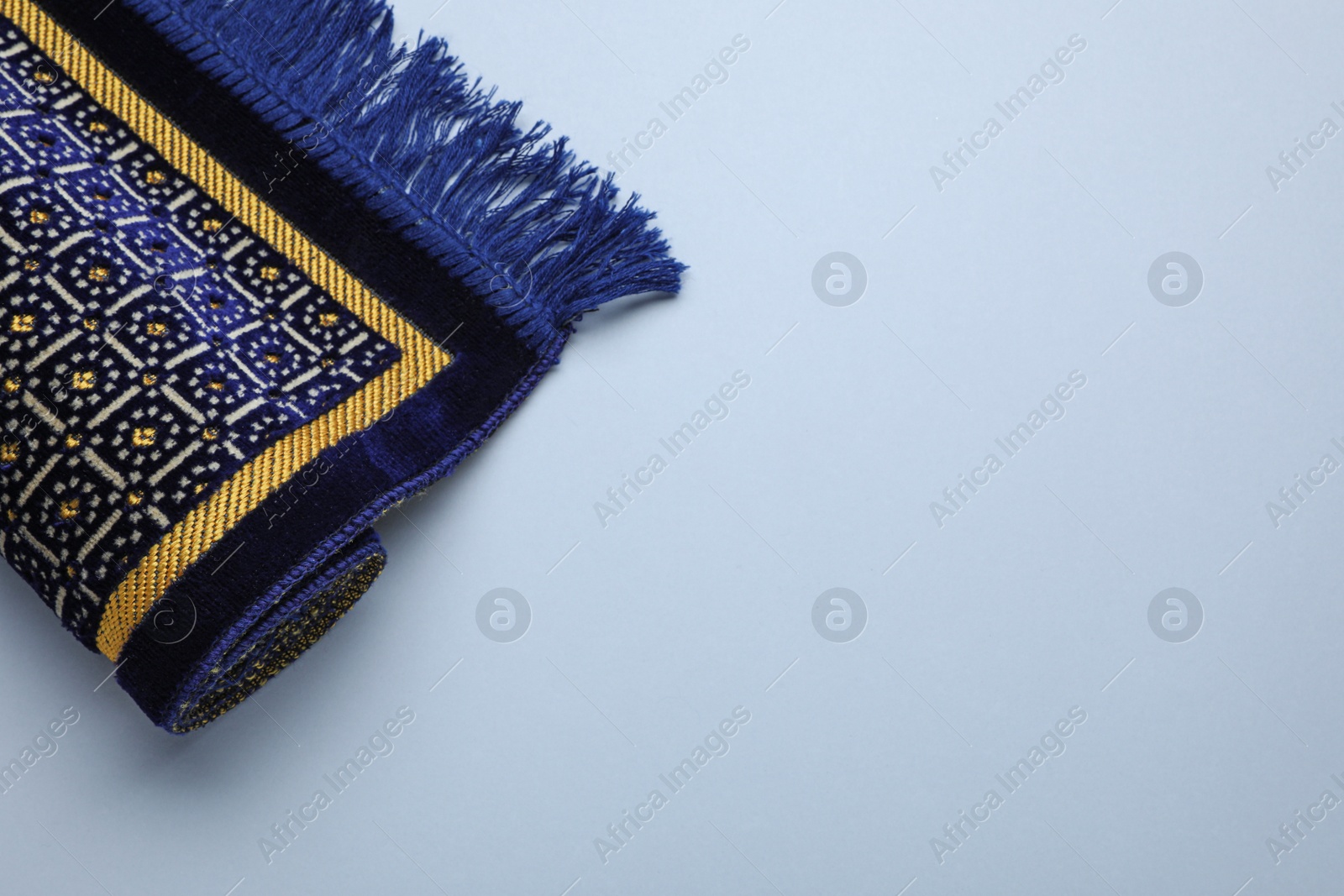 Photo of Muslim prayer rug on light background, above view. Space for text