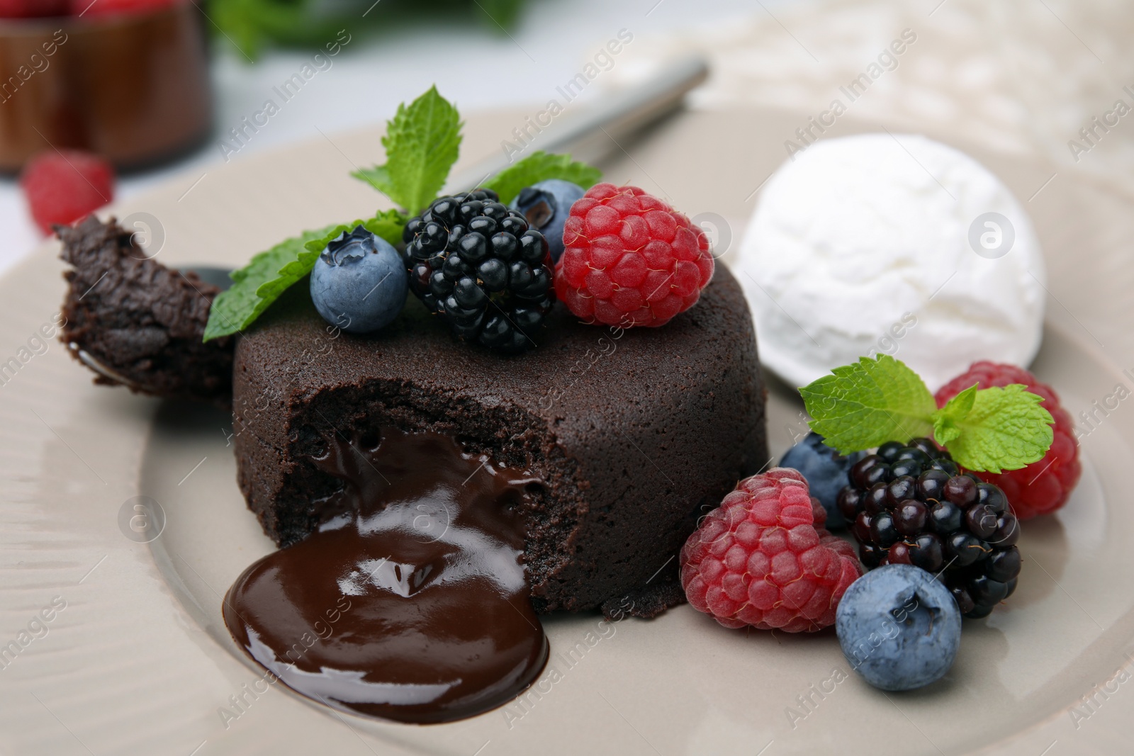 Photo of Delicious chocolate fondant served with fresh berries and ice cream on plate, closeup