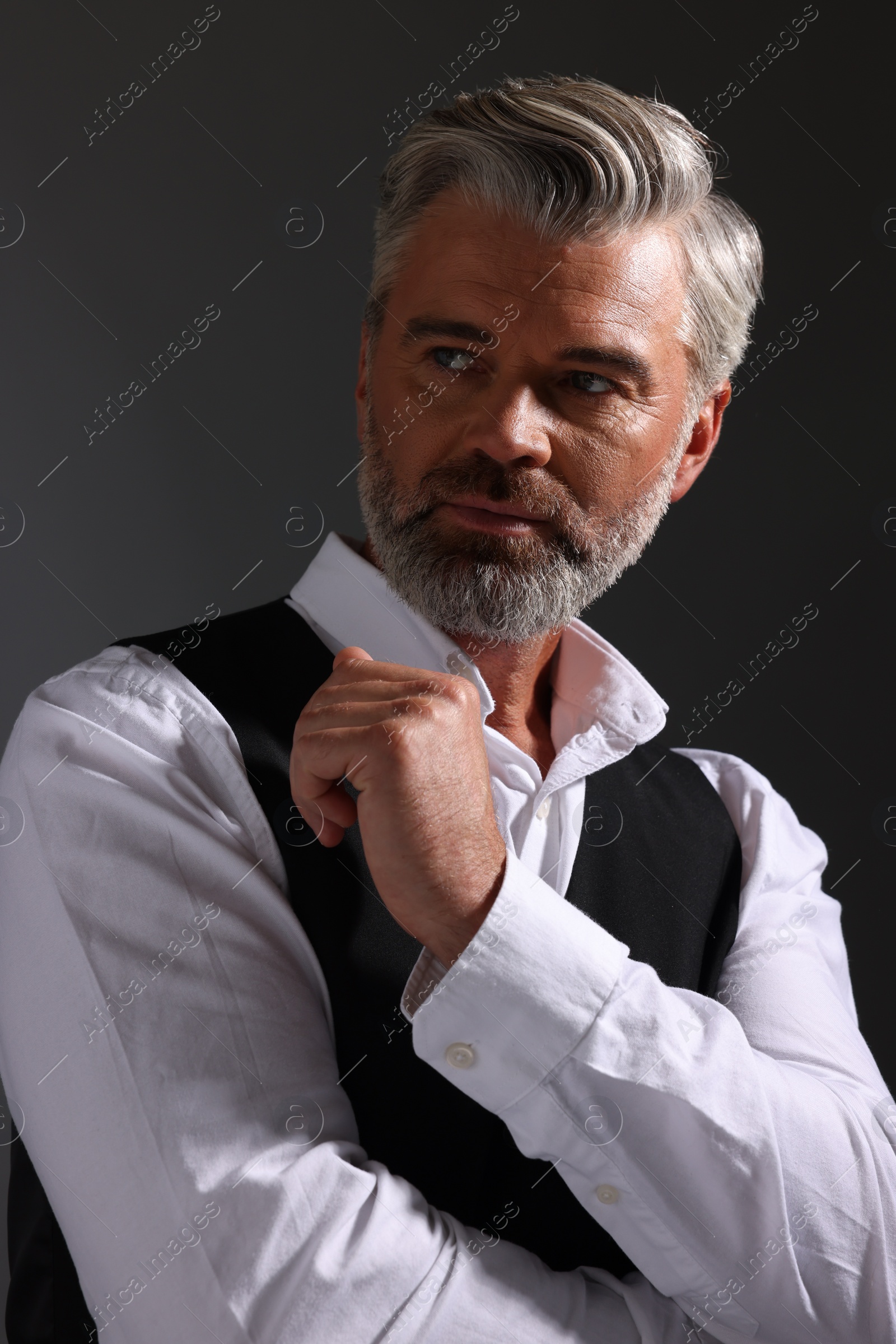 Photo of Portrait of confident man with beautiful hairstyle on dark background