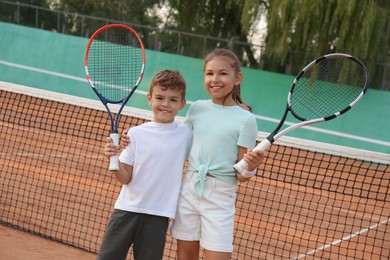 Photo of Happy children with tennis rackets on court outdoors