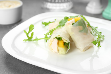 Photo of Delicious rolls wrapped in rice paper served on grey table, closeup