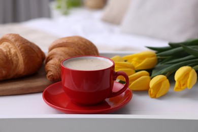 Photo of Morning coffee, croissants and flowers on white wooden tray indoors