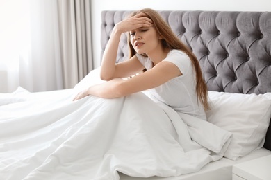 Photo of Young woman with terrible headache sitting in bed