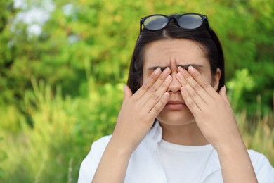 Young woman suffering from eyestrain outdoors on sunny day