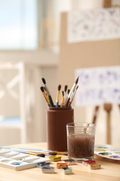 Photo of Composition with watercolor paints on wooden table in workshop