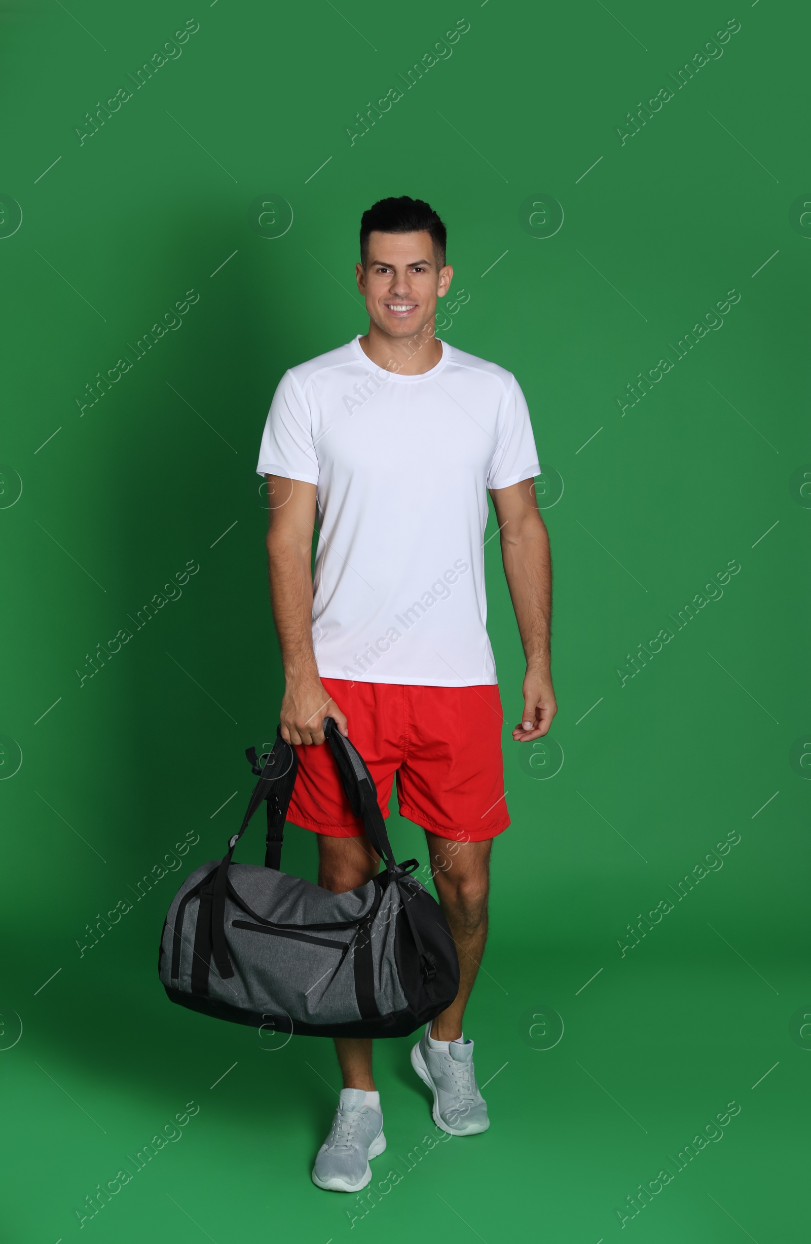 Photo of Handsome man with sports bag on green background